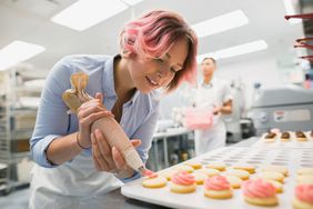 Pastry chef piping cookies pink icing commercial kitchen