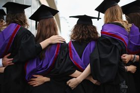 一群戴着帽子、穿着长袍的大学毕业生在摆姿势拍照
