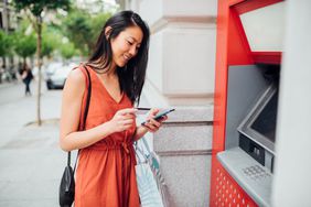 一名亚洲妇女用她的银行账户从自动取款机上取钱