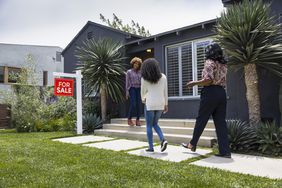 一个房地产经纪人在一所待售的房子外和两个女人打招呼。