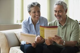 an older couple reading pamphlets on sofa