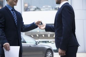 汽车销售员把一辆新车的钥匙交给一个年轻的商人