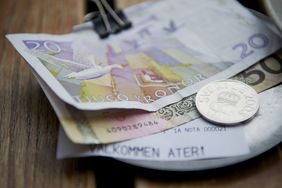 瑞典克朗钞票和一枚硬币放在木制桌上，代表在瑞典投资。