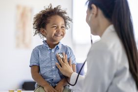 女医生用听诊器听小男孩的心。