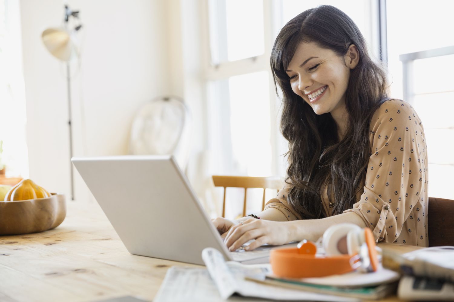 微笑的女人在桌子上使用笔记本电脑