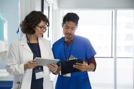 一名医生和一名护士在平板设备上查看信息。”width=