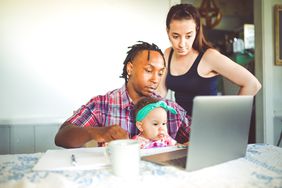 一位非裔美国父亲和他的女儿一起在电脑上工作。