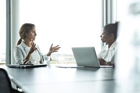 Two women colleagues speaking in office conference room