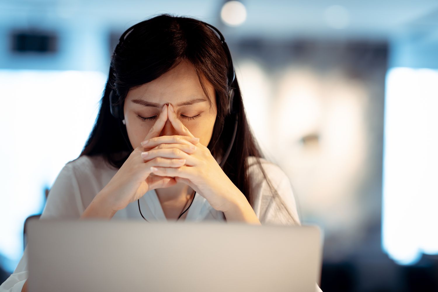 一位女士坐在笔记本电脑屏幕后，带着忧虑的表情休息着。