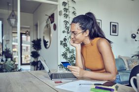 女人拿着信用卡，看着笔记本电脑