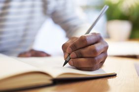 一个男人用钢笔在笔记本上写字的左手特写