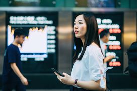 young woman with phone considers stock market numbers