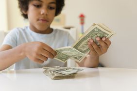一个小男孩在桌子上数美钞。