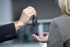 销售人员在汽车展销厅递给妇女车钥匙