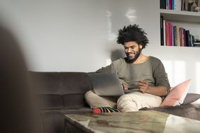 一个男人坐在客厅的沙发上，拿着笔记本电脑和信用卡＂>
          </noscript>
         </div>
        </div>
       </div>
       <div class=