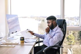 一个男人坐在他的办公桌前，决定他正在考虑投资的公司的现金流。