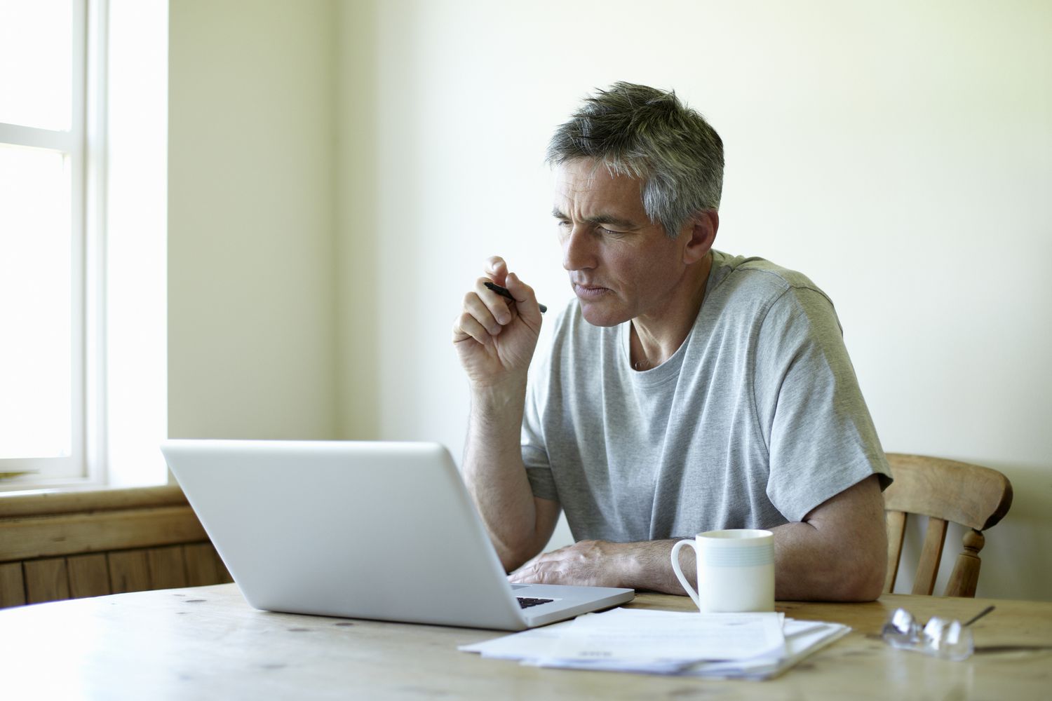 一个男人坐在厨房桌子前用笔记本电脑