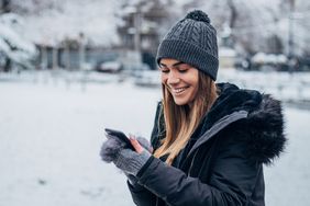 女人在冬天大衣和帽子看智能手机站在雪”>
          </noscript>
         </div>
        </div>
       </div>
       <div class=