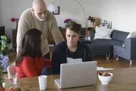 父母在家里用笔记本电脑和儿子聊天。