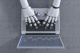 机器人手在笔记本电脑键盘上打字，代表当日期货交易。