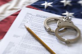 用手铐将税单放在美国国旗上，代表着逃税可能带来的法律麻烦。