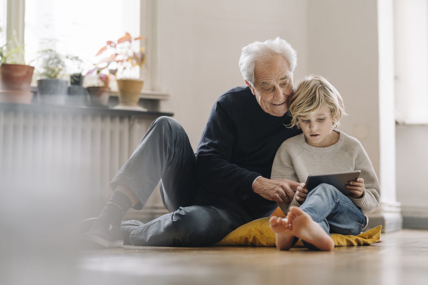 一个老人和一个孩子一起在地板上看书。