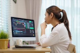 女人坐在桌子上分析股票在电脑屏幕上