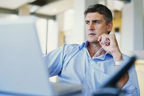 Businessman sitting in front of a laptop in an office, frowning