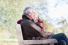 微笑的老年夫妇在公园长椅上拥抱