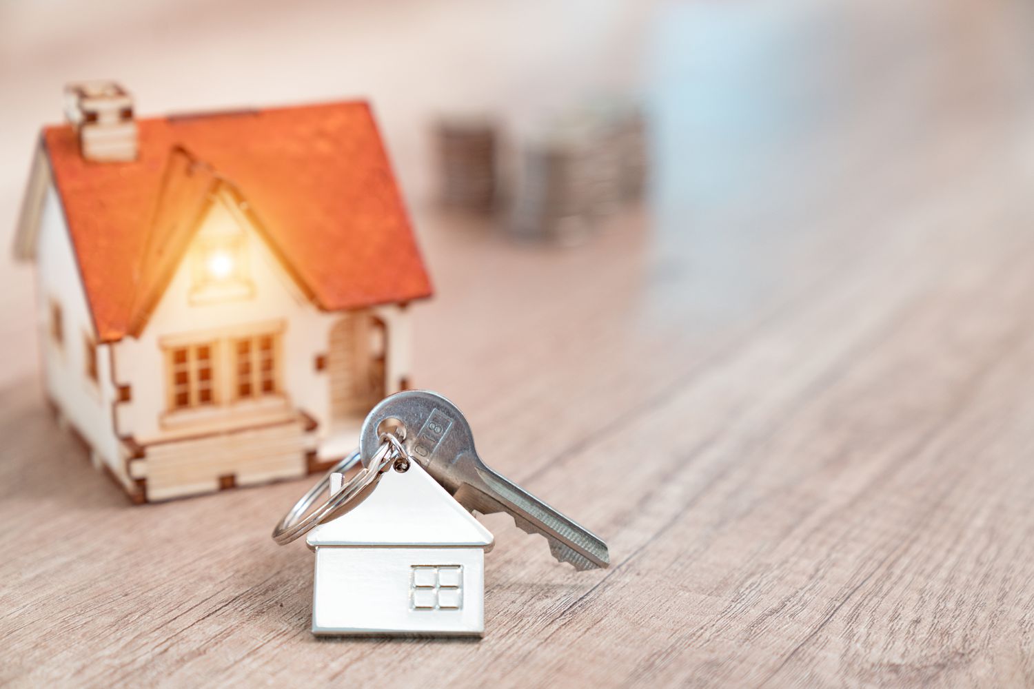 房子钥匙房子形状的钥匙扣放在木制地板概念房地产、移动家里或租赁财产”class=