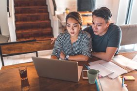 Serious young couple planning budget over laptop at table.