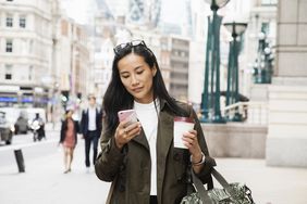女商人走在城市里看智能手机