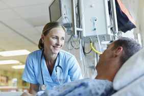 Smiling doctor looking at patient in hospital bed.