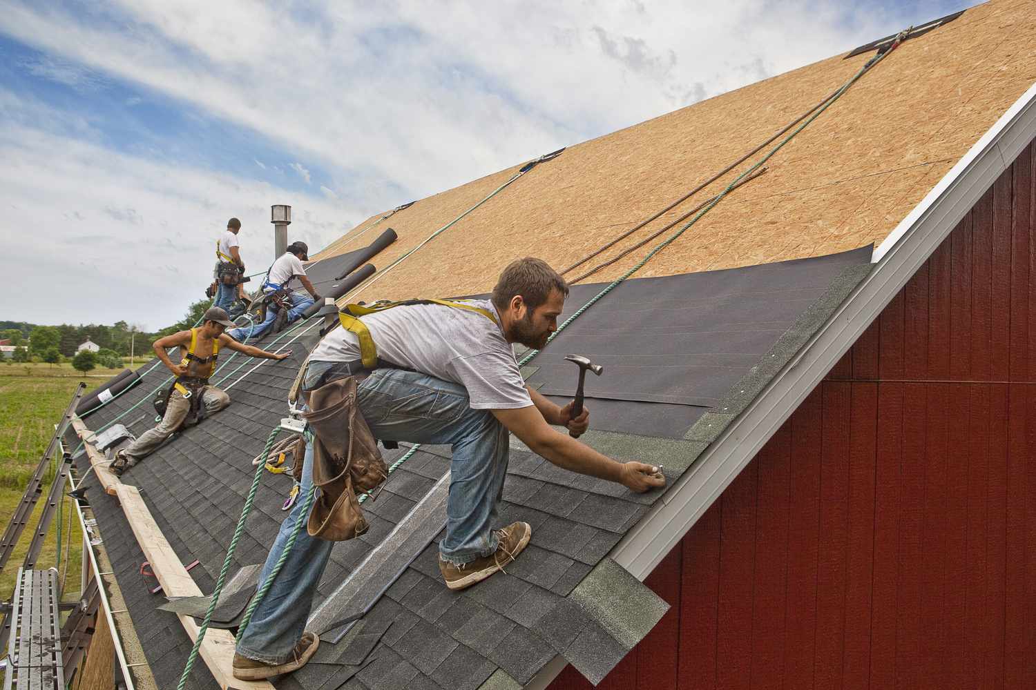 一组工人安装一个新建筑的屋顶。”class=