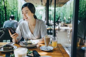 一位女士在吃饭时使用手机。