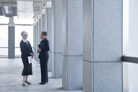 两名接近退休年龄的联邦雇员在一栋联邦大楼的走廊上交谈。