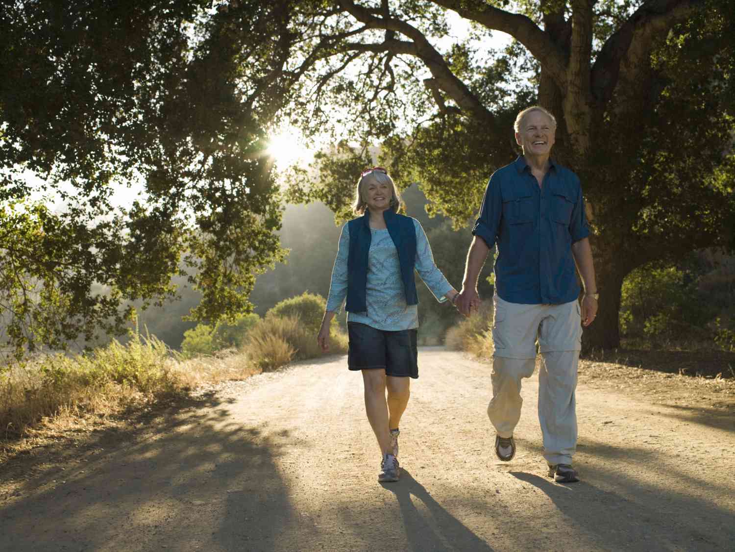 微笑的退休夫妇在银行有足够的存款，在阳光明媚的公园散步＂class=