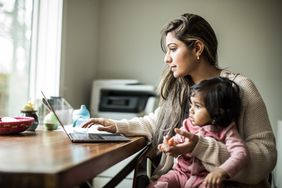 年轻的母亲多任务在家里的笔记本电脑和婴儿的女儿”>
          </noscript>
         </div>
        </div>
       </div>
       <div class=