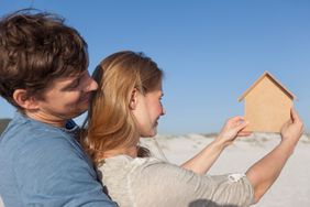 一对夫妇计划在未来的海滨别墅站在海滩上看着一个纸板剪出的房子。＂>
          </noscript>
         </div>
        </div>
       </div>
       <div class=