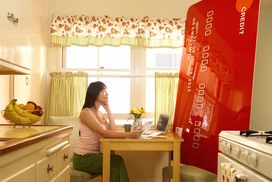 一个女人在厨房里看着一张巨大的信用卡”width=
