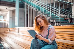 A person looks at their tablet while sitting.