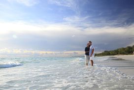 夫妇在海滩上站在水里”width=