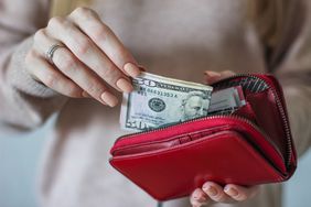 一名妇女将现金放入钱包中存钱