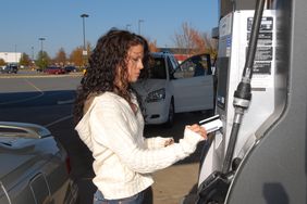 年轻女子用信用卡支付汽油加油站。