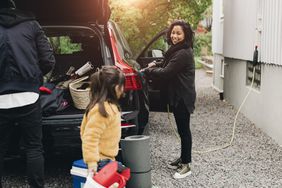 一个女人在给她的车充电，而她的家人却在给车装东西