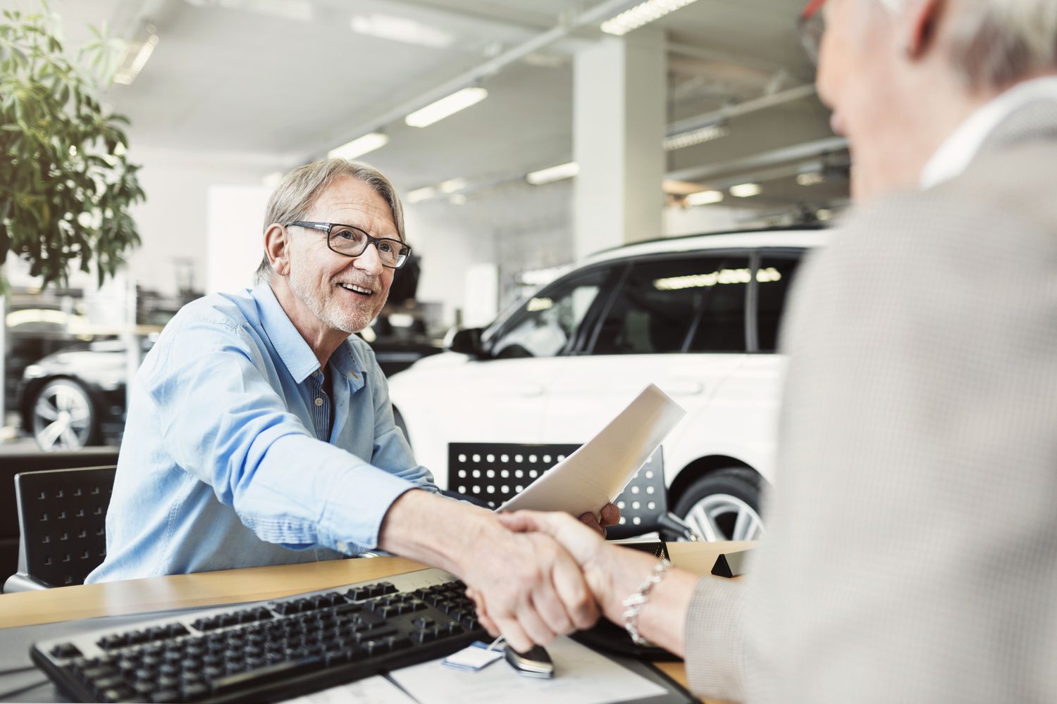一名男子在购买汽车后与他的汽车经销商握手