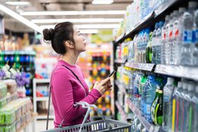 亚洲女性在超市购物时使用智能手机