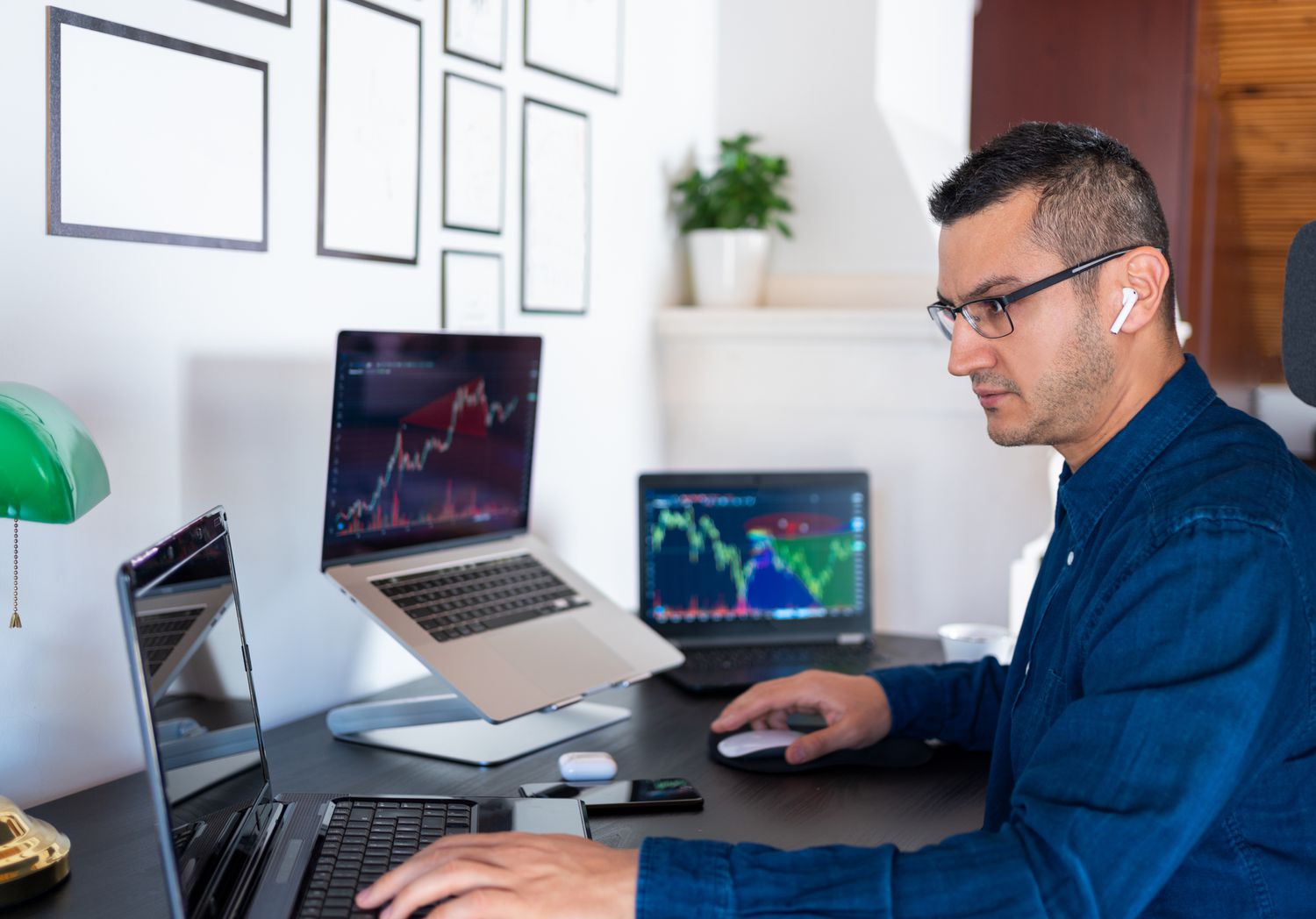 男子在家里办公室的笔记本电脑屏幕上分析市场图表