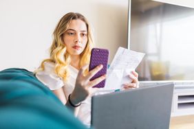 年轻女子用笔记本电脑看学生贷款报表和手机