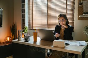 在一个黑暗的房间里，穿着西装的女人坐在电脑前的桌子前